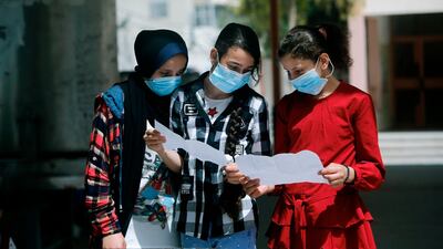 Palestinian school girls wearing face masks due to the COVID-19 coronavirus pandemic view their end of year certificates upon receiving them at a school in Gaza City. AFP