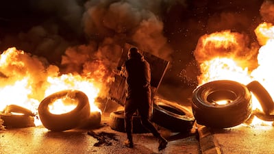 A protester walks near burning tyres in the occupied West Bank. AFP
