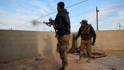 A member of the Iraqi security force fires his weapon, while another looks on, during clashes with Islamic State militants.