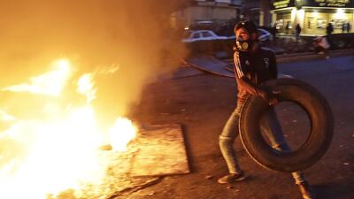 A protester throws a tyre onto a burning barricade during ongoing demonstrations in Beirut. AFP