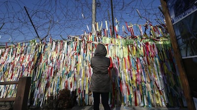 A woman reads messages on ribbons hanging on a wire fence wishing for the reunification of the two Koreas at the Imjingak Pavilion near the border village of Panmunjom, which has separated the two Koreas since the Korean War, in Paju, north of Seoul. Lee Jin-man / AP Photo