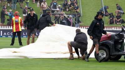 Ground staff race to put the covers on the pitch as rain falls during day one of the first Test. AFP
