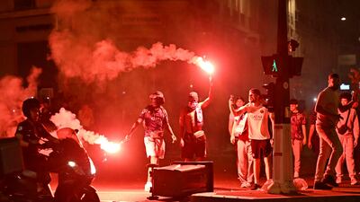 PSG supporters gather holding flares on a street in Paris. AFP