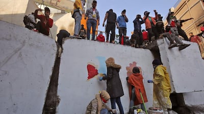 Iraqi protesters paint on a concrete barrier. AFP