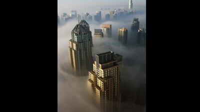 Thick early morning fog sits amongst the buildings in the Dubai marina. Mark Asquith / The National