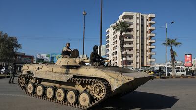 Fighters of Hayat Tahrir Al Sham ride on a military vehicle during what they said was security checks to find 'remnants' of ousted Syrian president Bashar Al Assad's force, in Wadi Al Dahab neighbourhood in Homs, Syria. Reuters