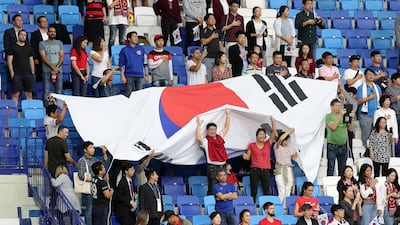South Korean supporters sing the national anthem of their country before the game.