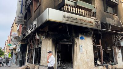 A man stands next to a bank destroyed by the protests. Reuters