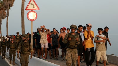 Troops escort migrants on Spain's enclave of Ceuta, situated on the northern shores of Morocco's Mediterranean coast. Reuters