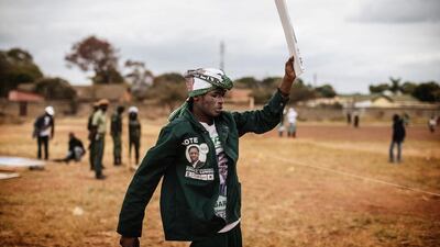 A man walks with a placard as supporters of the Zambian ruling party Patriotic Front, and its incumbent president Edward Lungu, cheer during his presidential campaign closing rally. Gianluigi Guercia / AFP Photo