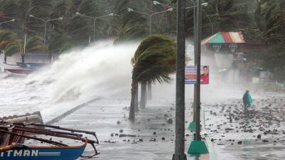 A resident walks past high waves pounding the sea wall in the city of Legaspi, Albay province. Charism Sayat / AFP Photo