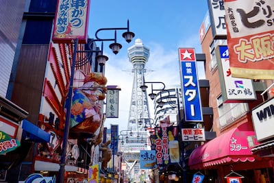 Shop signs and restaurants against the Tsutenkaku tower in Osaka's Shinsekai entertainment district. Getty Images