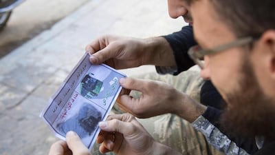 Opposition fighters look at a flyer reportedly distributed by the government encouraging people to leave a rebel-held area of Aleppo on October 20, 2016. Karam Al Masri/AFP
