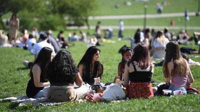 Groups sit in the sunshine at Primrose Hill, London. EPA