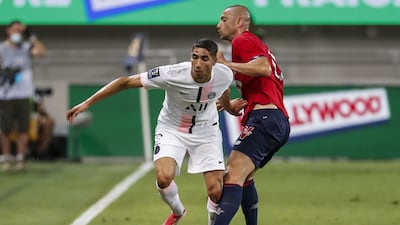 Paris Saint-Germain's Moroccan defender Achraf Hakimi fights for the ball with Lille's Turkish forward Burak Yilmaz.