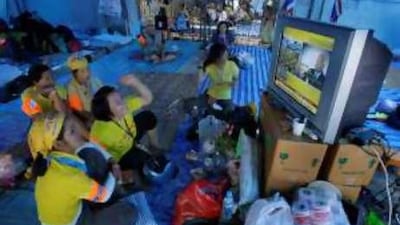 Protesters react as they listen to Samak Sundaravej, the Thai prime minister, in a live radio broadcast outside Government House in Bangkok.