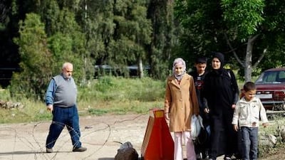 Lebanese soldiers stand guard as a Syrian family crosses on foot through an unofficial border into Wadi Khaled in northern Lebanon on April 29, fleeing the political unrest in Syria.