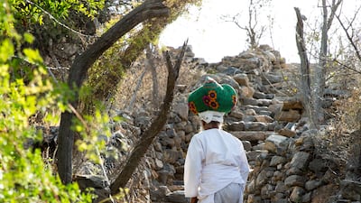 An Omani villager, Nasser, 80, with freshly-picked roses wrapped up in a cloth on his head in Al Ayn Village. Nasser has his own rose garden and factory where he processes the flowers.