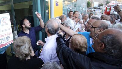 Pensioners who do not own ATM cards queue to enter a bank branch to withdraw part of their pensions. Stefanos Rapanis / EPA
