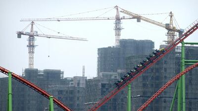 A roller coaster makes its initial climb at Wanda City against a backdrop of construction cranes on apartment buildings. Mark Schiefelbein / AP