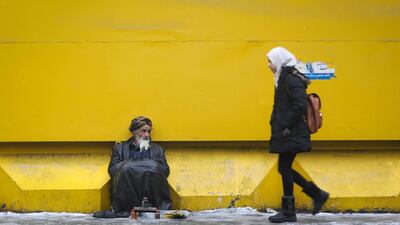 An Afghan shoe-shiner sits alongside a street as he waits for customers, in Kabul, Afghanistan. EPA