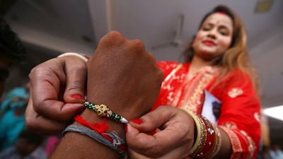 A woman ties a rakhi on her brother's wrist. EPA