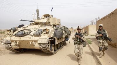 US infantry soldiers use a Bradley fighting vehicle for cover outside Baghdad International Airport in 2003