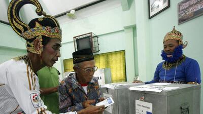 Indonesian electoral workers in costumes assist an elderly man at a voting stations in Yogyakarta, Indonesia. Bimo Satrio / EPA