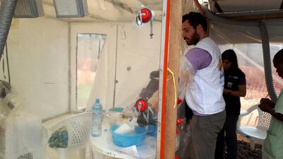 A health worker reaches into the Dr Kojan-designed Cube isolation tent where Ebola patients can be treated safely. Courtesy of Jennifer Lazuta/ALIMA