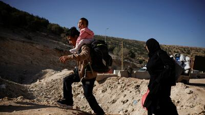 A boy carries a child while crossing from Lebanon into Syria on foot at the Masnaa border crossing. Reuters