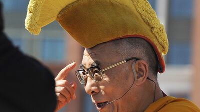 July 16, 2011: Tibetan spiritual leader the Dalai Lama gestures to his head-wear as he arrives to bless the Anacostia River in Washington with sand from a mandala mixed with water during a ceremony marking the end of the annual Kalachakra. AFP Photo / J???