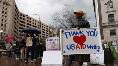 People gather outside the Ronald Reagan Building during a 'clap out in support of USAID staff. AFP