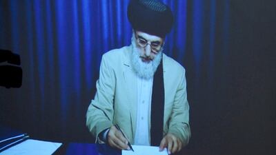 Gulbuddin Hekmatyar is displayed on a video projector screen as he signs a peace deal with Afghan president Ashraf Ghani on September 29, 2016. Wakil Kohsar/AFP
