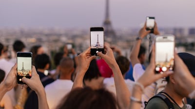 Crowd of tourists taking photos of the Eiffel. They are waiting for dusk when lights on tower turning on