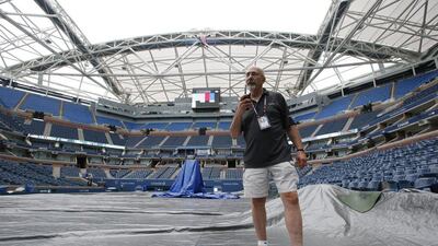 Richard Reidel walks on a tarp-covered court at Arthur Ashe Stadium as he tests the sound system after the women's semi-final matches were postponed until Friday because of rain at the US Open. Kathy Willens / AP