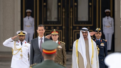 Sheikh Mohamed and Mr Al Assad stand for the national anthem. Presidential Court
