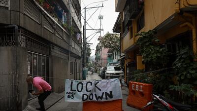 A government worker crosses signage at a village under lockdown in Manila, Philippines.