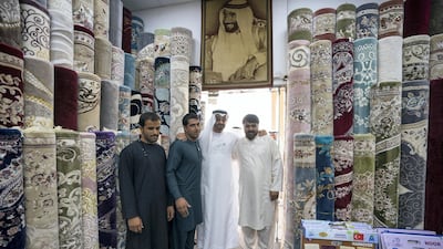 Sheikh Mohammed bin Zayed stands for a photograph with staff at Al Safa Carpet shop, in the carpet market of the Mina Zayed Port. Ryan Carter for the Crown Prince Court - Abu Dhabi