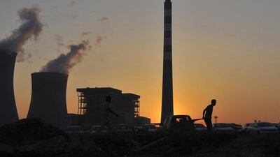 A worker pulls a cart in front of the smoking chimneys of a power plant in Hefei, Anhui province, on October 24, 2014. China's economy, the world's second largest, grew at its slowest pace since the global financial crisis in the September quarter and risks missing its official target for the first time in 15 years, stoking worries about global growth as well as the risk of social discontent. Reuters