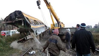 Rescue workers lift a railcar at the site where a train transporting soldiers crashed in the Giza neighbourhood of Badrashin on Tuesday. Khaled Elfiqi / EPA