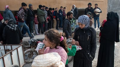 A displaced Syrian girl carries a bag of bread in a stadium which has been turned into a makeshift refugee shelter in Idlib, Syria. Getty