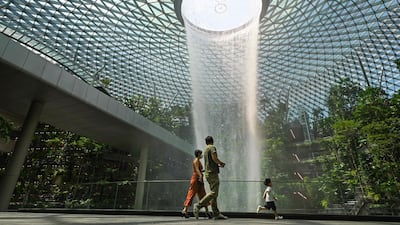 A family walks past the rain vortex at Jewel Changi Airport in Singapore. Border closures and a testing regime have allowed the city state to escape the worst of the pandemic in Asia. AFP