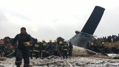 Nepalese rescuers stand near a passenger plane from Bangladesh that crashed at the airport in Kathmandu, Nepal. Niranjan Shreshta / AP Photo