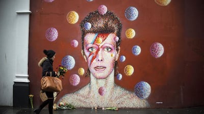 Flowers are left below a mural of David Bowie on the wall of a Morley’s store in Brixton, London, the singer’s birthplace. Anthony Devlin / PA via AP
