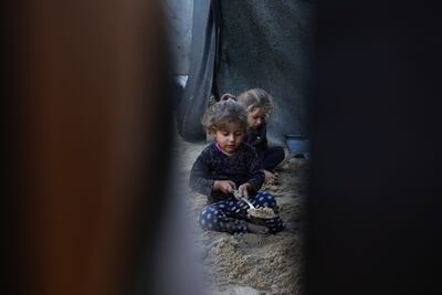 Displaced Palestinian children play with sand at a camp in Khan Younis. AP