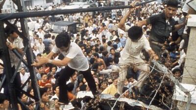 An American Marine guard dislodges two Vietnamese men trying to climb over barbed-wire wall into American Embassy to escape advancing North Vietnamese troops on the last day of the US involvement in the Vietnam War, in April 1975. Image by Nik Wheeler / Corbis