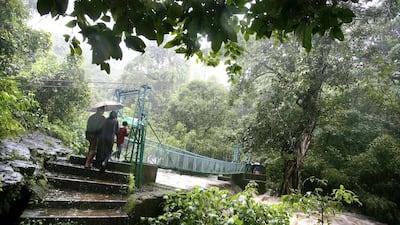 Indian tourists walk across a bridge traversing a free flowing river at Virajpet. Dibyangshu Sarkar / AFP