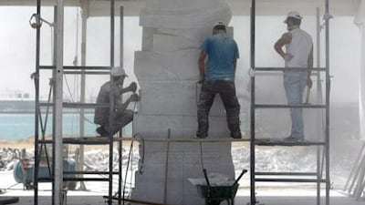 With the Arabian Gulf in the background, Husam Chaya, right, supervises assistants as his piece takes shape at the Armed Forces Officers Club.