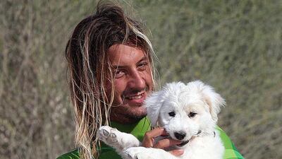 Babis Kokmotos, a kiteboarding instructor, poses with rescued puppy Elsa, at the Jumeirah Beach in Dubai. Satish Kumar / The National