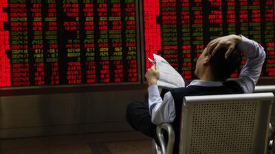 An investor with a newspaper looks at stock market data displayed on an electronic board at a securities brokerage house in Beijing, China. EPA